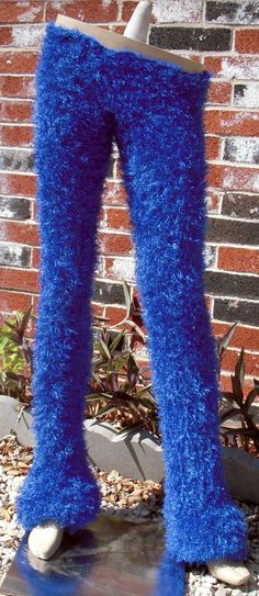 there is a fake blue furry leg in front of a brick wall and planter