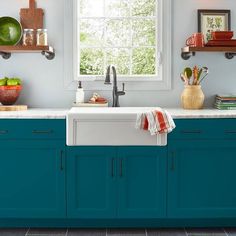 a kitchen with blue cabinetry and white counter tops, along with open shelves on the wall