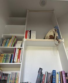 a book shelf filled with lots of books next to a bag and purse on top of it