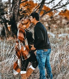 a man and woman are standing in the tall grass