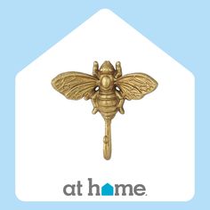 a golden bee on a blue background with the at home logo below it