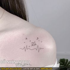 the back of a woman's shoulder with a cat and stars tattoo on it