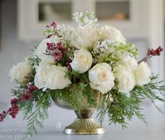 a vase filled with white flowers and greenery