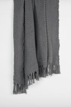 a gray knitted scarf hanging on a white wall