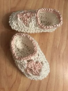 two crocheted baby shoes sitting on top of a wooden floor