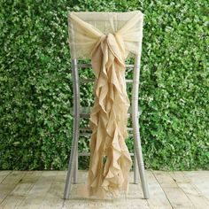 a chair with a bow tied to it sitting in front of a wall covered in greenery