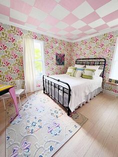 a bedroom decorated in pink and white with floral wallpaper on the walls, flooring and rugs