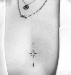 a black and white photo of a woman's chest with a cross tattoo on it