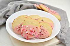 a white plate topped with cookies covered in pink frosting and sprinkles