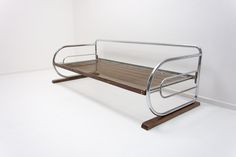 a metal and wood bench sitting on top of a white floor next to a wall