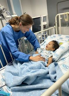 a female nurse tending to a baby in a hospital bed