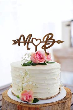 a white cake with pink flowers and an arrow on top