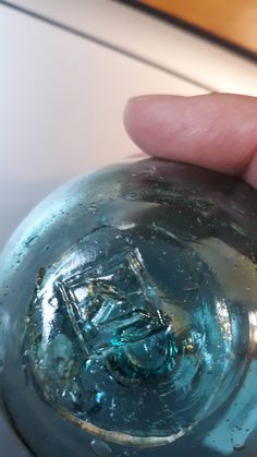 a hand is holding a glass ball with water on it and the bottom half has a small hole in it