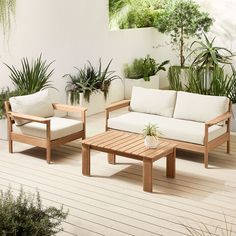 a couch and table on a deck with potted plants