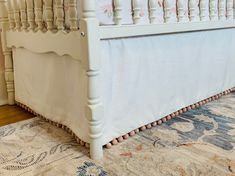 a white bed sitting on top of a wooden floor next to a rug and wall