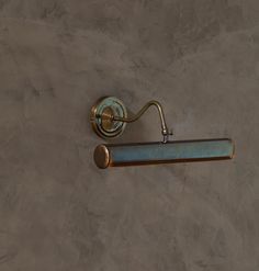 an old fashioned brass toilet paper dispenser on a gray wall with a blue handle