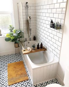 a white bathroom with black and white tile flooring, a bathtub in the middle