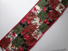 a close up of a tie with red and green flowers on it, next to a ruler