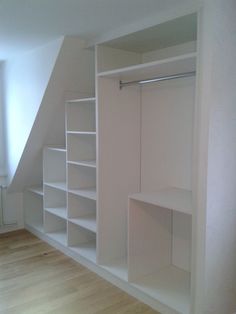 an empty room with white shelving in it and wood flooring on the other side