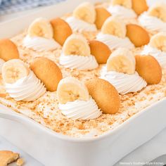 a dessert dish with banana slices and whipped cream on top, in a white pan