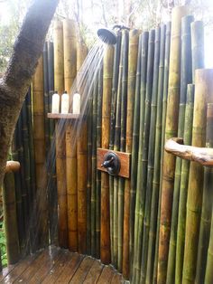 an outdoor shower is made out of bamboo sticks and has water flowing from it's faucet