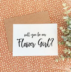 a card with the words will you be our flower girl? on it next to some flowers