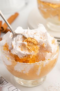 a bowl filled with whipped cream on top of a white table next to other plates