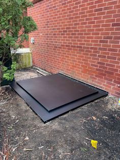 a black sheet laying on the ground in front of a brick wall