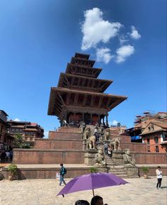 two people sitting under an umbrella in front of a building with a pagoda on top