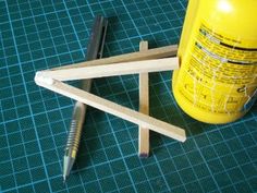 some wood sticks are next to a yellow bottle and screwdriver on a table