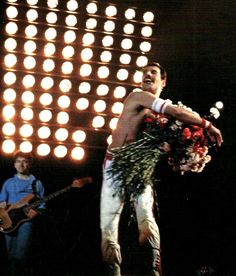 a man standing on top of a stage holding a bunch of flowers