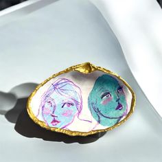 two women's faces are painted on an egg shell