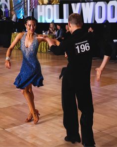 a man and woman are dancing on the dance floor in front of hollywood's sign