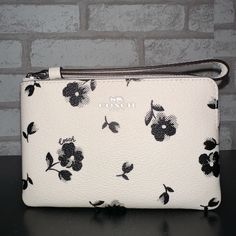 Printed Coated Canvas And Smooth Leather Two Credit Card Slots Zip-Top Closure, Fabric Lining Wrist Strap Attached 6 1/4" (L) X 4" (H) X 1/2" (W) White Bag With Wrist Strap As Gift, Everyday White Bag With Wrist Strap, White Wristlet For Daily Use In Spring, Chic White Wristlet For Gift, White Pouch Wristlet As Gift, White Everyday Wallets For Spring, Chic White Wristlet For Everyday Use, White Clutch With Wrist Strap For Everyday Use, Elegant White Wristlet For Everyday Use