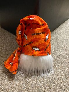 an orange and white hat with the denver logo on it sitting on top of a carpeted floor