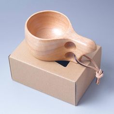 a wooden bowl sitting on top of a cardboard box next to an empty bottle opener