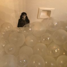 a room filled with lots of white balls and a small figure in the middle of it