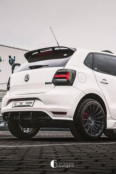 the rear end of a white car parked on top of a parking lot next to a building