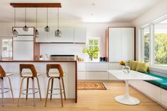 a kitchen with white cabinets and counter tops next to a breakfast nook, bar stools