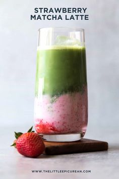 strawberry matcha latte in a glass next to a strawberries on the side