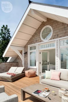 an outdoor living area with couches, tables and chairs on the wooden flooring