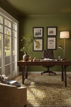 a living room with green walls and pictures on the wall, a chair, desk and lamp