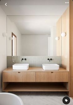 two white sinks sitting on top of a wooden counter