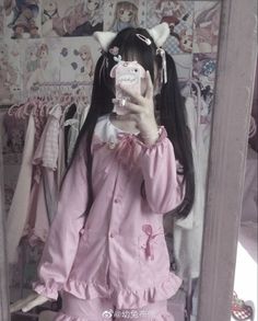 a woman taking a selfie in front of a mirror wearing a pink dress and cat ears