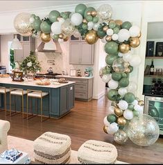 a living room filled with furniture and balloons in the shape of an arch on top of a kitchen island