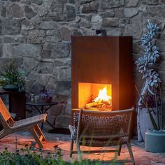 two chairs sitting next to each other in front of a fire place with a stone wall behind them