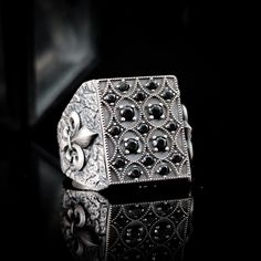 Another ring with black onyx stones. Designed in rectangular form, this ring draws attention with textured surfaces on its body and Fleur de Lis symbols on both sides. This ring, which has a structure that can be considered large in size, will be a part of your style and will complement your elegance. The product is meticulously crafted from pure 925 sterling silver and is of exceptional quality. The ergonomic design ensures a comfortable fit for everyday wear. Each ring is custom-made according Rectangular Black Engraved Ring, Black Rectangular Engraved Ring, Black Engraved Rectangular Ring, Black Engraved Rectangular Jewelry, Black Rectangular Engraved Jewelry, Luxury Rectangular Onyx Ring, Luxury Onyx Men's Ring As A Gift, Black Sterling Silver Rectangular Signet Ring, Luxury Onyx Rectangular Rings