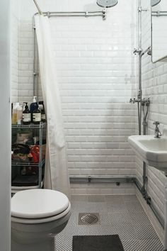 a white toilet sitting next to a sink in a bathroom under a shower curtain and tiled floor