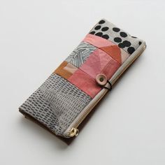 a small wallet is decorated with patchwork and polka dot fabric, which has a zippered closure