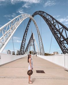 a woman standing in front of a bridge with a hat on it's head